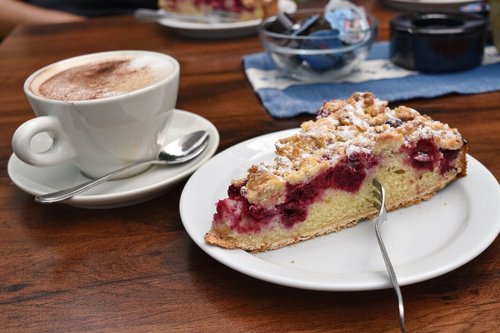 Ein Stück Kirsch-Streuselkuchen und ein Cappuccino.