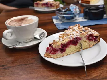 Ein Stück Kirsch-Streuselkuchen und ein Cappuccino.